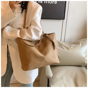 Detail of a khaki nylon tote bag showing its lightweight texture and shoulder strap