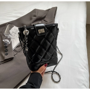 Close-up of black quilted bucket bag with chain strap and metallic twist lock closure