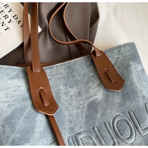 Detailed view of blue stonewashed denim tote bag with premium brown leather straps