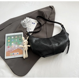 Detail of black geometric moon bag with plush bunny charm on grey blazer and white bedsheet