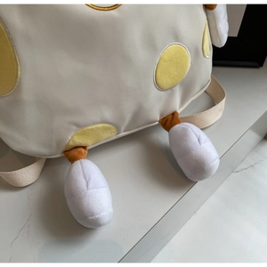 Detail shot of canvas backpack featuring yellow polka dots and 3D plush duck feet decor