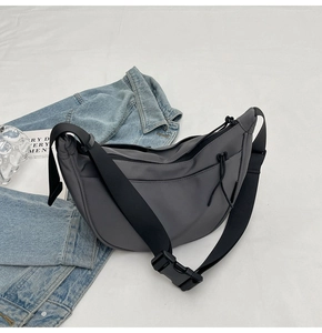 Macro shot of dark grey nylon dumpling bag with adjustable strap and buckle detail