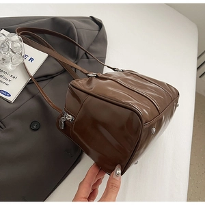 Detail view of brown leather bag with silver protective metal studs and smooth zipper