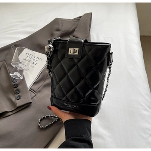 Close-up of black quilted bucket bag with silver chain strap and metal swivel lock
