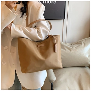 Detail of khaki oxford cloth tote bag with leather logo patch and luxury nylon finish