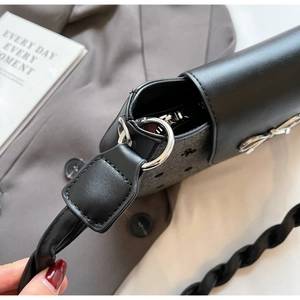 Detail der schwarzen Ledertasche mit gepunktetem Schleifendruck und gewebtem Riemen