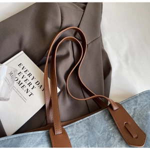 Close-up of blue denim tote bag with cross star pattern and brown leather straps