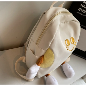 Detail view of cute off-white canvas backpack featuring a yellow smiley face embroidery