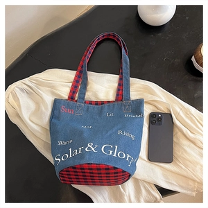 Dettaglio della borsa in denim con fodera a quadri rossi e scritte Solar & Glory