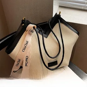 Détail de sac cabas plissé crème avec bordure noire et sangle textile avec lettrage