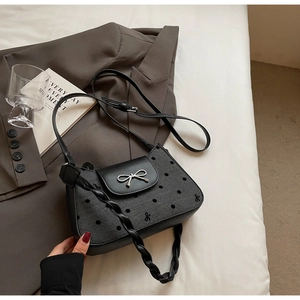Detail der schwarzen gepunkteten Handtasche mit Silberschleife und geflochtenem Riemen
