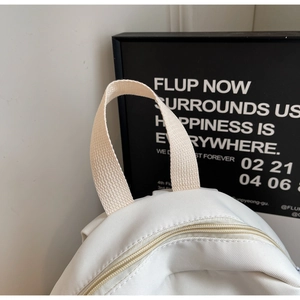 Detailed macro view of off-white canvas bag with cross-grain handle and top metal zipper