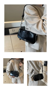 Close-up of black glossy leather underarm bag with S-shaped silver metal wave hardware