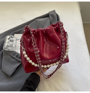 Detail of dark red quilted bucket bag with pearl handle and silver rivet accents