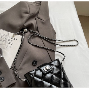 Macro detail of black quilted leather bucket bag with silver metal ball chain adjuster