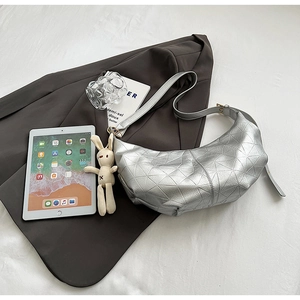 Detail of silver geometric dumpling bag with a cute rabbit pendant on a brown blazer