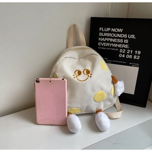 Close-up of cute cream canvas backpack with yellow polka dots and plush cartoon character limbs