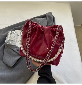 Close-up of red quilted bucket bag with silver studs and elegant pearl handle