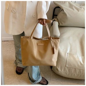 Close-up of the khaki nylon tote bag featuring a leather patch with CAROLMANI logo detail
