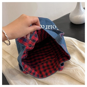 Dettaglio della borsa in denim con ampia fodera a quadri rossi e tessuto interno
