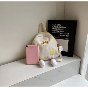 Detailed shot of cute canvas backpack with smiley embroidery and plush limbs decoration