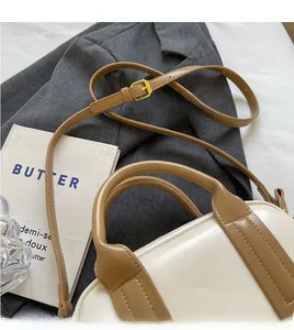 Detail of adjustable shoulder strap with gold metal buckle on two-tone boston bag