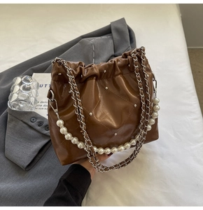 Detail of brown quilted leather bucket bag with pearl chain strap and silver rivets