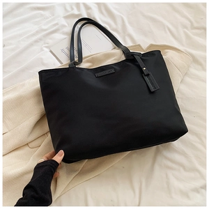 Detail of waterproof black oxford tote bag showing CAROLMANTI logo and smooth texture