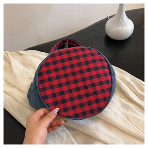 Dettaglio della borsa a secchiello in denim con motivo a quadri rosso e nero sul fondo
