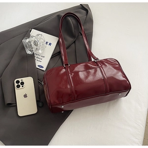 Top view of burgundy glossy patent leather boston bag with silver hardware and strap