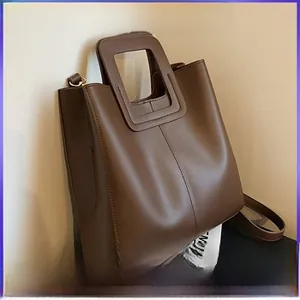 Détail d'un sac cabas marron café en cuir avec poignées carrées ajourées et bandoulière