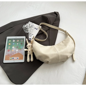 Detail of off-white dumpling bag with geometric texture and cute plush bunny charm