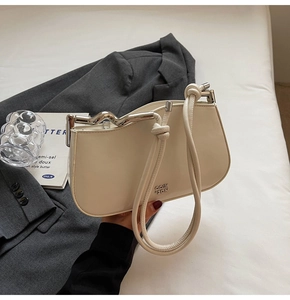 Detail of cream white PU shoulder bag with silver wavy metal handle and logo brand logo