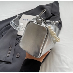 Detailansicht der silbernen Handtasche mit Metallic-Textur und elegantem Perlen Griff