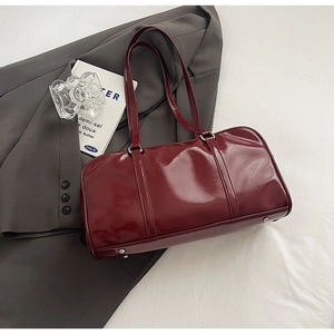 Detail of burgundy patent leather handbag with glossy finish and silver base studs