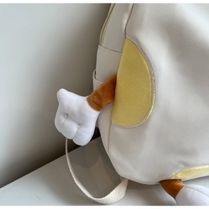Detail of canvas backpack featuring yellow accents and a cute brown plush cartoon arm