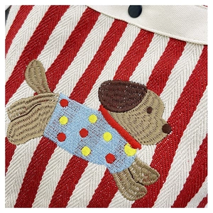 Détail de la broderie d'un chiot dessin animé sur un sac seau en toile à rayures