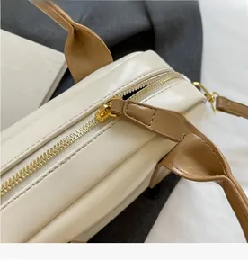 Detailed macro view of the smooth gold metal zipper and stitching on the cream Boston bag