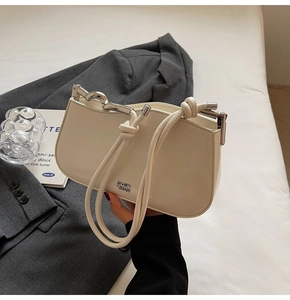 Close-up of cream white leather underarm bag with silver logo and knotted strap detail