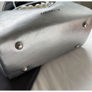 Details der silbernen Metallic-Ledertasche mit Perlengriff und schützenden Bodennieten