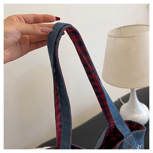 Dettaglio del manico in denim resistente con fodera a quadri rossi e neri