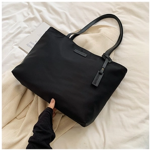 Detail of black large capacity oxford tote bag with Carolmarti logo and top handles