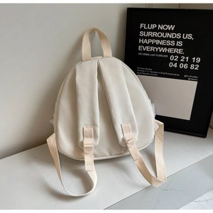 Detailed back view of a cream canvas backpack with adjustable wide straps and minimalist design