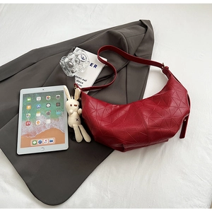 Detailed view of red crescent shoulder bag with geometric patterns and rabbit pendant