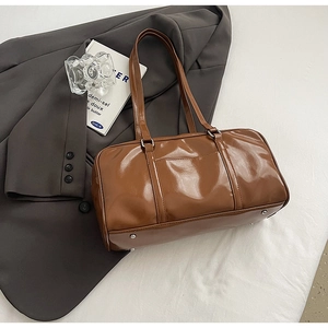 Detail of glossy brown Boston bag featuring silver hardware and protective metal feet