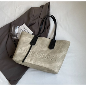 Detailed texture of beige creased leather tote bag with embossed MEIDUOLA logo