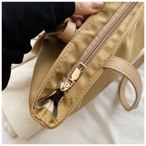 Detail of golden zipper and lychee texture handle on khaki oxford tote bag
