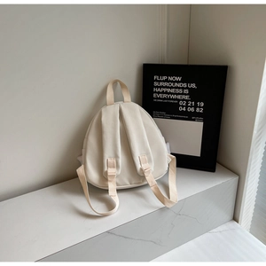 Rear view of a cream white nylon mini backpack with wide straps and top handle detail