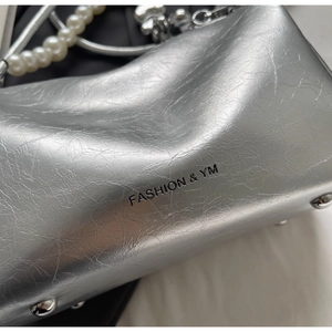 Detail der silbernen Metallic-Umhängetasche mit Faltenstruktur, Nieten und Perlenkette