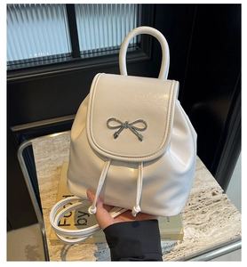 Detailed macro of white glossy mini backpack with silver metal bow and top handle